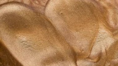 Küçük metal bir spatula kullanarak altın sıvı dudak parlatıcısı ya da tırnak cilası karıştırmak. Altın parıltılı arka plan. Boşluğu kopyala