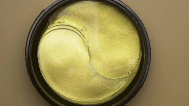 Kavanozdan plastik kaşıkla altın göz bantları alıyor. Kozmetik ürün konsepti. yakın plan