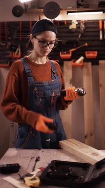 Keresteye vida sokmak için elektrikli tornavida kullanan kadın marangoz. Bir atölyede ahşap işçiliği. Boşluğu kopyala
