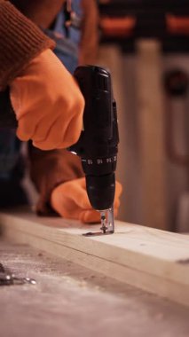 Marangoz elektrikli tornavidayla keresteye vida sokuyor. Bir atölyede ahşap işçiliği. yakın plan