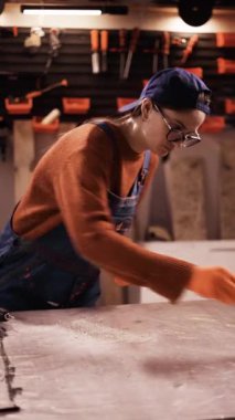 Kadın marangoz atölyede ahşap masa parçası boyuyor. DIY ve hobi kavramı