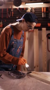 Küçük bir atölyede çalışan profesyonel kadın marangoz. Sanatçı kadın kereste detaylarını siyah yağ ya da leke ile boyuyor. Doğrama ve marangozluk konsepti