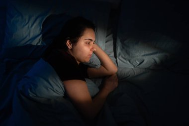 Yatakta uykusuz bir gece. Uyku bozukluğundan muzdarip genç bir kadın yorgunluktan uyuyamıyor. en üstteki görünüm
