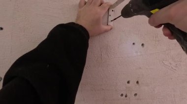 Man 'in sondaj duvarındaki vidaları söktüğü yakın plan. POV