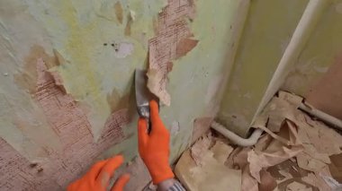 POV erkek çalışanı eski duvar kağıtlarını spatulayla temizliyor. Ev onarımı ve yenileme konsepti. Boşluğu kopyala