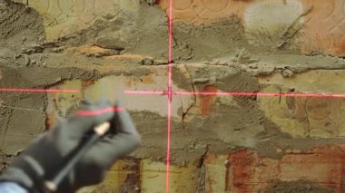 Yenileme sırasında kırmızı lazer ışınını kullanarak tuğla duvarı kalemle işaretleyen yapıcıyı kapat