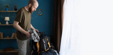 Şapkalı sakallı bir adam sırt çantasını çantasıyla birlikte iç mekanda kamp macerasına başlamaya hazır. Boşluğu kopyala