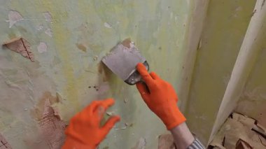 POV erkek çalışanı eski duvar kağıtlarını spatulayla temizliyor. Ev onarımı ve yenileme konsepti. Boşluğu kopyala