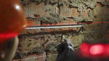 Lazer seviyesindeki kırmızı çizgileri kullanarak duvarı ölçen bir kadın inşaat işçisinin yakın çekimi. Boşluğu kopyala