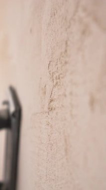 El işçisinin yakın çekimi, duvardaki pürüzsüz alçı yüzeyi havan cilası ile parlatıyor. dikey video