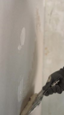 Ev tamiri için duvara ıslak alçı sürerken yakın plan. Dikey video