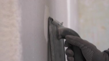 İşçi, alçı duvar yüzeyini zımparalamak için Emery aletini kullanıyor. yakın plan