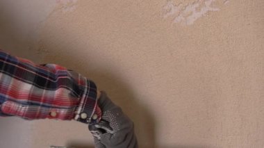 Profesyonel müteahhit, ev yenileme projesi sırasında el hareketine odaklanarak macun bıçağı ve mala kullanarak duvar yüzeyine ince alçı tabakası uyguluyor. yakın plan