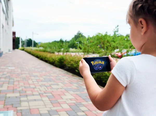 Liten flicka spelar en Pokemon Go spel utomhus. — Stockfoto