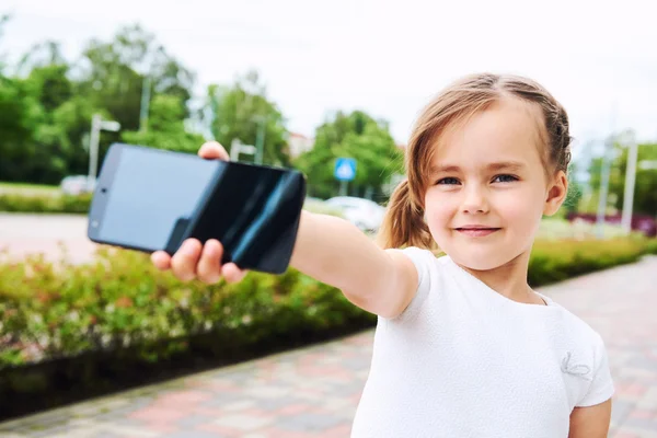 Очаровательная маленькая девочка со смартфоном на улице . — стоковое фото
