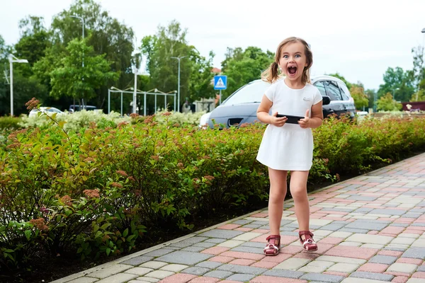Adorabile espressiva bambina con uno smartphone all'aperto — Foto Stock