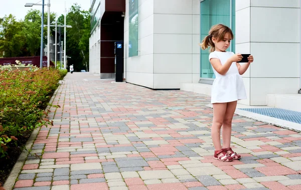 Маленькая девочка со смартфоном на улице — стоковое фото