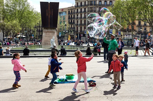 儿童抓肥皂泡在加泰罗尼亚广场 — 图库照片