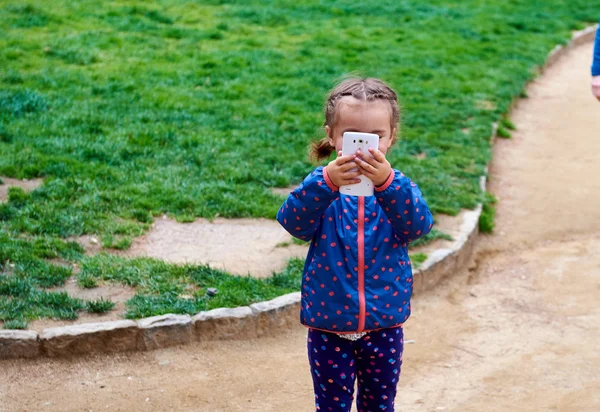 Mała dziewczynka robi wideo lub zdjęcie z telefonem komórkowym na zewnątrz — Zdjęcie stockowe