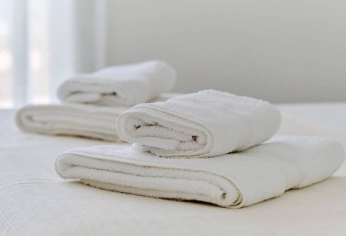 Yatak odasında beyaz havlular uzanıyor, manzarayı kapatıyor.