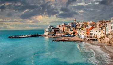 Bulutlu gökyüzü arka planının üzerindeki bulutlu günbatımında antik İtalyan kasabası Bogliasco 'nun antik balıkçı köyü. Akdeniz sularının turkuaz körfezi. Seyahat ve tatil kavramı. İtalya