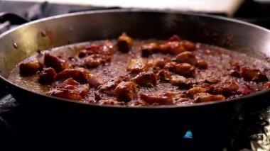 Paella yemeğinin geleneksel İspanyolca usulü. Gaz fırını, soslu deniz ürünlerini büyük, sığ bir tavada kızartıyor. Şef tavaya çiğ beyaz pirinç ekliyor, yavaş çekim yakın görüntü