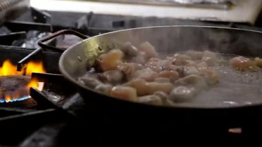 Gaz fırını şefini kullanarak sığ deniz mahsullerini kızartırken aynı zamanda mersin balığı ve karides karıştırıyor. Geleneksel İspanyol paella tabağı için malzemeler, ağır çekim.