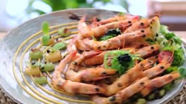 Salata ve bir dilim limonla servis edilen kabuksuz karidesleri yemeye hazır dönen tabak üzerinde yavaş çekim yakın görüntüsü. Restoran yemekleri.