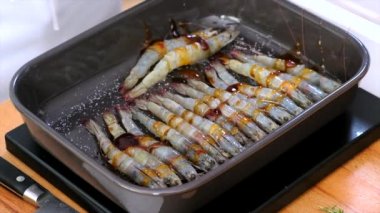 Kızartma tepsisinin içindeki kabuksuz, bbq soslu karidesleri yakından izleyin. Şef deniz ürünleri yemeği hazırla.