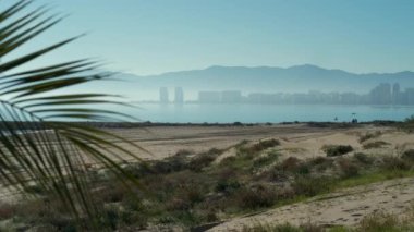 Boş kumlu plaj ve Cullera kasabasının silueti. Akdeniz Deniz Burnu, bulutlu gökyüzü ve sisli şehir manzarası. Valencia Eyaleti. Costa Blanca, İspanya