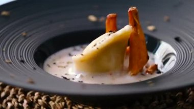 Ev yapımı ördek konfeti, krema soslu porsiyon ve dönen siyah tabakta altın chanterelle mantarı servis edilir. İtalyan mutfağı, restoran ana yemek konsepti.