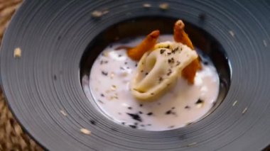 Ev yapımı ördek konfeti, krema soslu porsiyon ve dönen siyah tabakta altın chanterelle mantarı servis edilir. İtalyan mutfağı, restoran ana yemek konsepti.