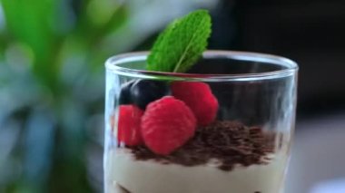 Bardakla yakından bakınca taze böğürtlen ve nane yaprağıyla süslenmiş tiramisu kahve aromalı İtalyan tatlısı servis ediliyor. Restoran yemekleri konsepti.