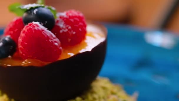在旋转的盘子慕斯进入一个巧克力半球模具装饰新鲜的覆盆子和蓝莓 接近上方的视野 餐厅甜点概念 — 图库视频影像