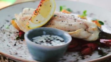 Yavaş çekim deniz levreğini BBC sebzeleri, sos ve dönen tabakta bir dilim limon ile kapatın. Restoran ana yemek konsepti.