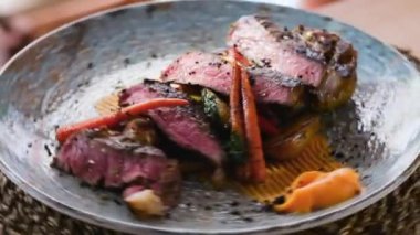 Yakın çekim, orta pişmiş biftek, bbq sebzeler ve sos ile servis edilir. Restoran ana yemek konsepti.