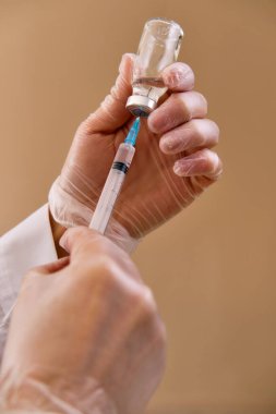 Kadın hemşire, salgın koronavirüse karşı kazanılmış bağışıklık sağlamak amacıyla şırınga ve aşı şişesi içeren koruyucu eldivenler giyer. Aşı takvimi kavramı