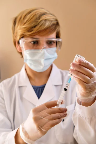 女性看護師は 流行性コロナウイルスに対する獲得免疫を提供することを目的として 注射器とワクチンバイアル用量を有する防護手袋眼鏡を着用する 予防接種スケジュールの概念 — ストック写真
