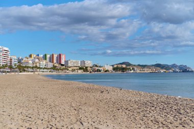 Vila Joyosa 'nın boş kumlu plajı ya da Villajoyosa turistik şehir silueti. Güneşli sıcak kış gününde sakin Akdeniz. Seyahat ve tatil kavramı. Alicante ili, Costa Blanca, İspanya