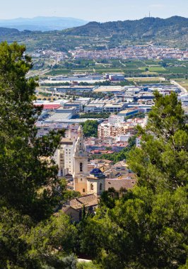 Xativa 'ya dikey görüntü, İspanyol kasabasına karşı dağ manzarası, üst manzara. Bereketli yeşil ağaçlar ve ünlü turistik köy manzarası, güneşli bir gün. İspanya