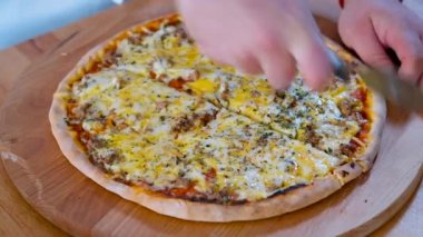 Manzarayı kapat, erkek şef pizzaları dilimlere ayırıyor. İtalyan mutfağı, fast food hazır yemek konsepti.