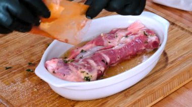 Manzaralı erkek aşçı elleri mutfakta et pişiriyor, domuz pirzolasına kırmızı biber döküyor, eti bira sosuna batırıyor. Gıda hazırlama süreci kavramı