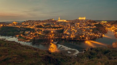 Gece sokak ışıklarıyla aydınlatılan hava aracı bakış açısı Toledo 'nun Tagus nehri ile çevrili tarihi bir şehir akşam manzarası. Castilla La Mancha. İspanya 