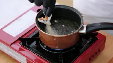 Yakın plan şefin eli içine bir tencere kaynamış yağ karidesi tempura yemek hazırlama, gurme, hareket konseptinde yemek koy.