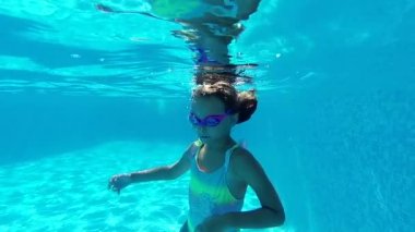 Sevimli 8 'li kızlar mayo giyer ve gözlük takar ve kameraya bakar. Yaz tatillerinde havuzda yüzerler. Aktif yaşam tarzı, yaz keyfi, spor aktivitesi konsepti. Yavaş çekim görünümü