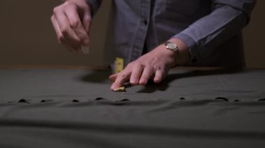 Profesyonel terzinin eli kapalıyken gri kumaşla çalışan tebeşir izleri yapmak için santimetre kullanılması gerekir. Stüdyoda moda tasarımcısı dikiş atölyesi konseptinde yeni koleksiyon giysileri tasarlıyor.