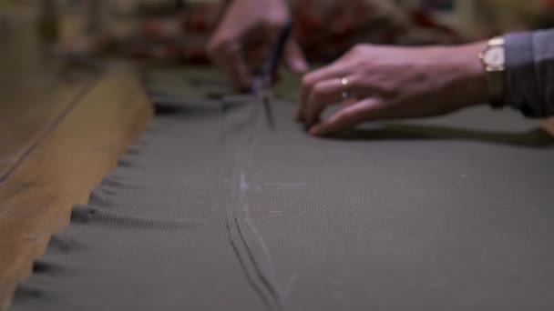 在缝纫车间 近距离裁缝师在桌面上用剪子剪裁面料 缝纫工用灰色纺织品缝制面料 时装设计师裁缝在工作室设计新的系列服装概念 — 图库视频影像
