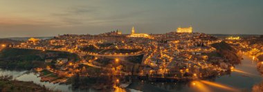Gece sokak ışıklarıyla aydınlatılan hava aracı bakış açısı Toledo 'nun Tagus nehri ile çevrili tarihi bir şehir akşam manzarası. Castilla La Mancha. İspanya 