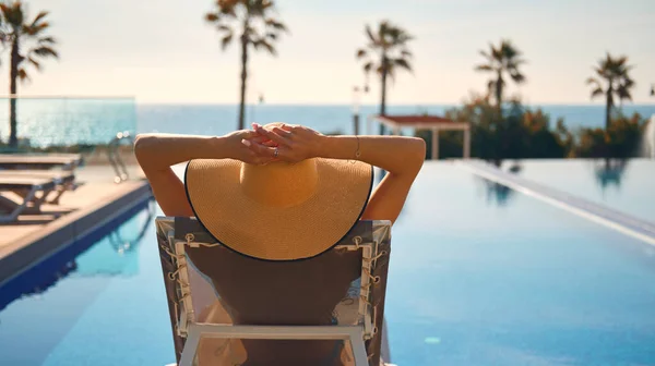 Vista Trasera Mujer Usar Sombrero Paja Tumbado Tumbona Junto Piscina — Foto de Stock