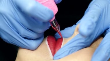 Dudakların mikro pigmentasyonu. Kadın makyaj ustası, müşteri dudaklarının pigmentini uygulayan bir makina. Güzellik ve estetik tedavi kavramı